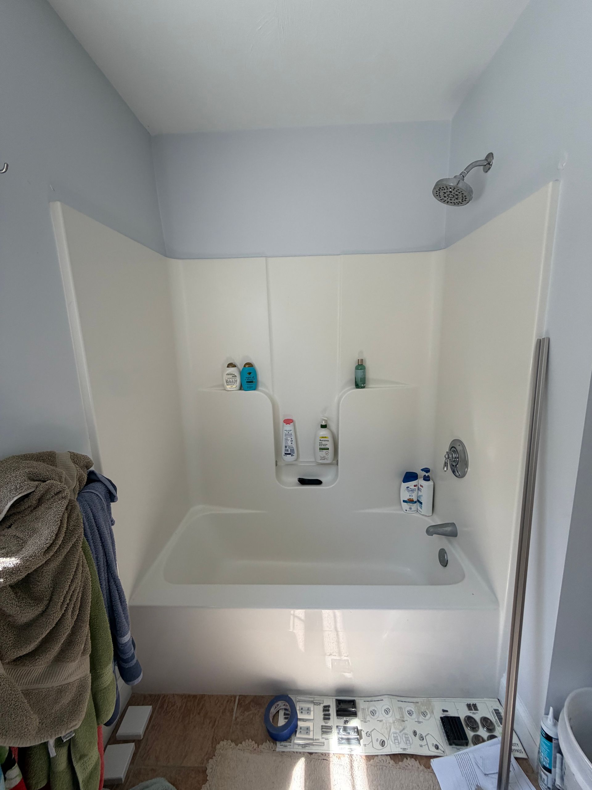 Small bathroom with a white bathtub, shower fixtures, and towels hanging on the left wall.