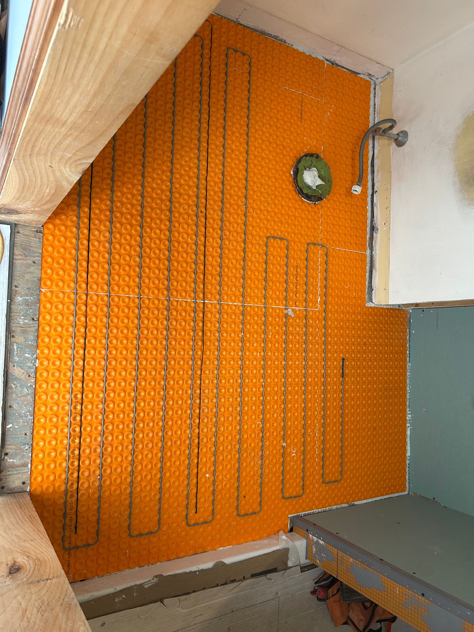 Orange decorative wall with black line patterns and a small green clock in a narrow indoor space