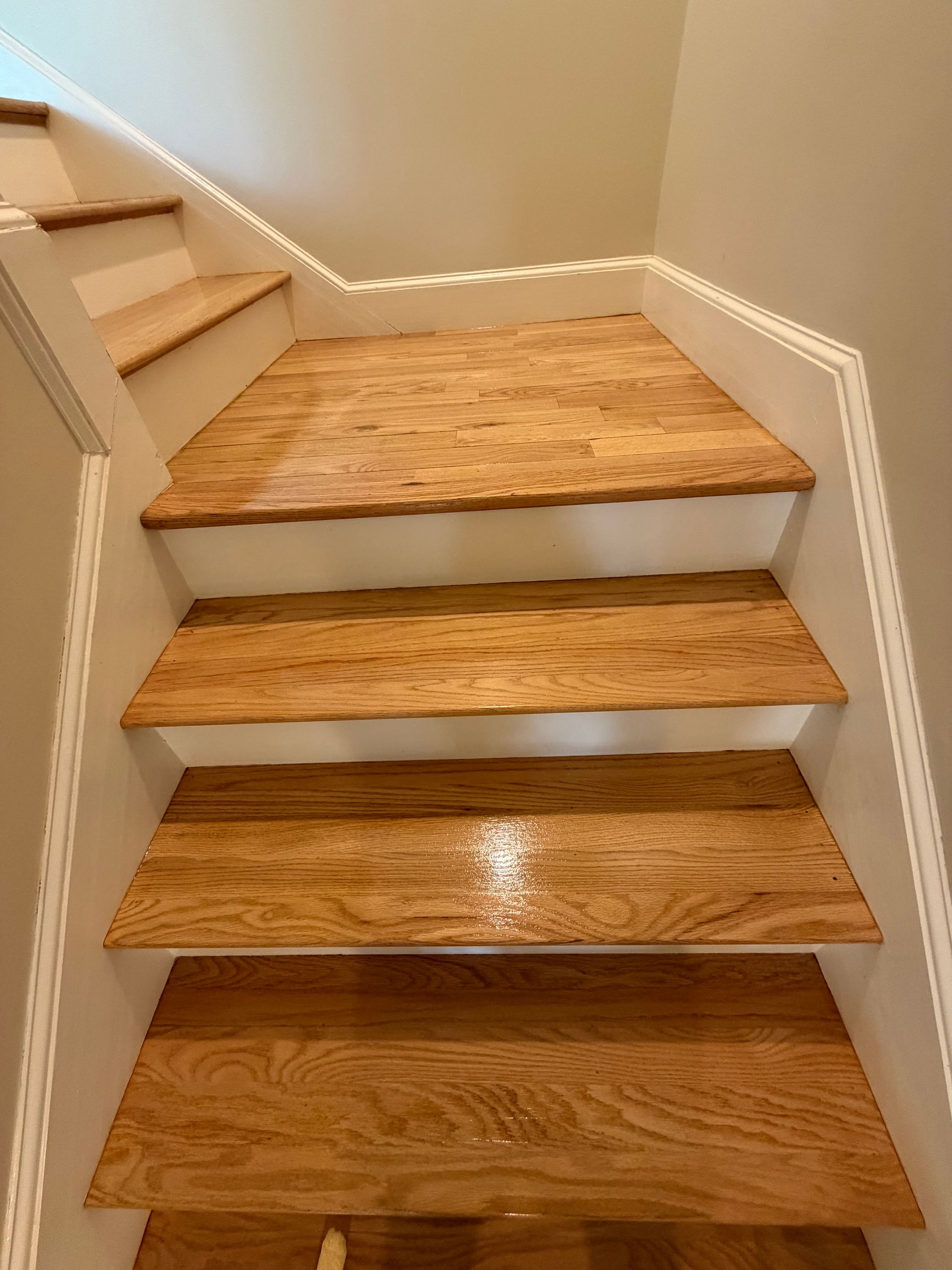 Wooden staircase with unfinished plywood treads and white trim in a home interior