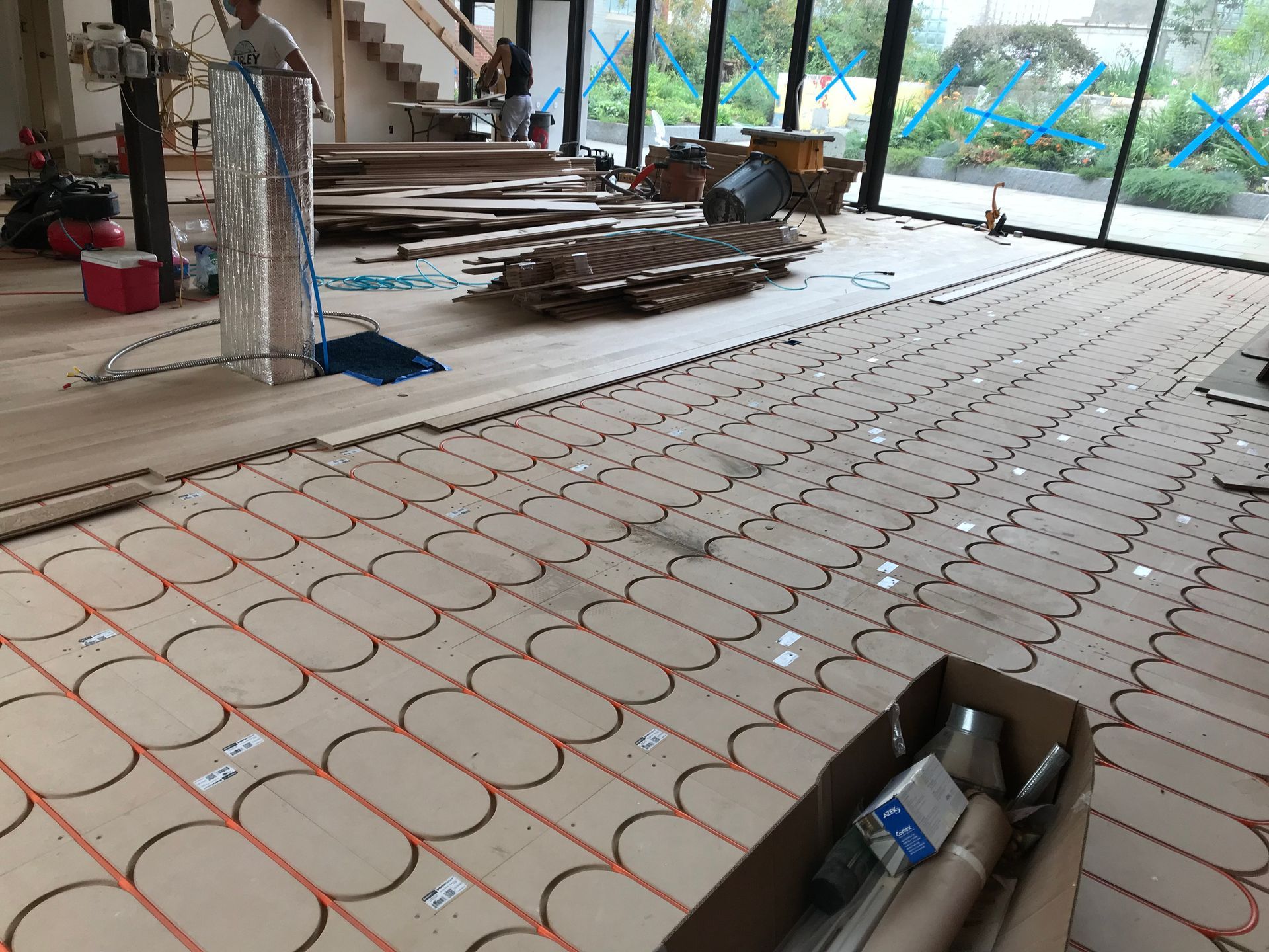 Construction site with floor heating tubes laid in a grid across a large room.