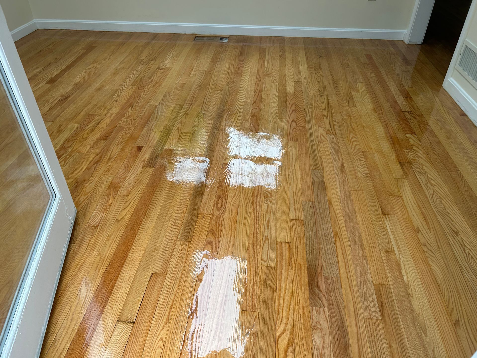 Empty room with hardwood floor and bright sunlight reflections on the wood.