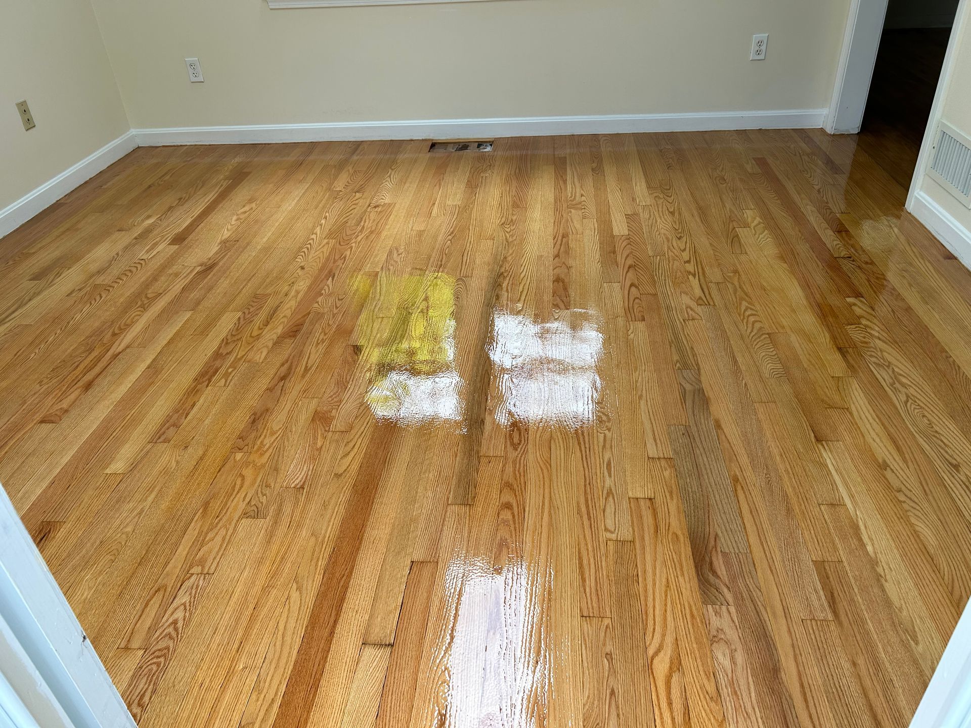 Shiny hardwood floor in an empty room with bright reflections from windows or lights.