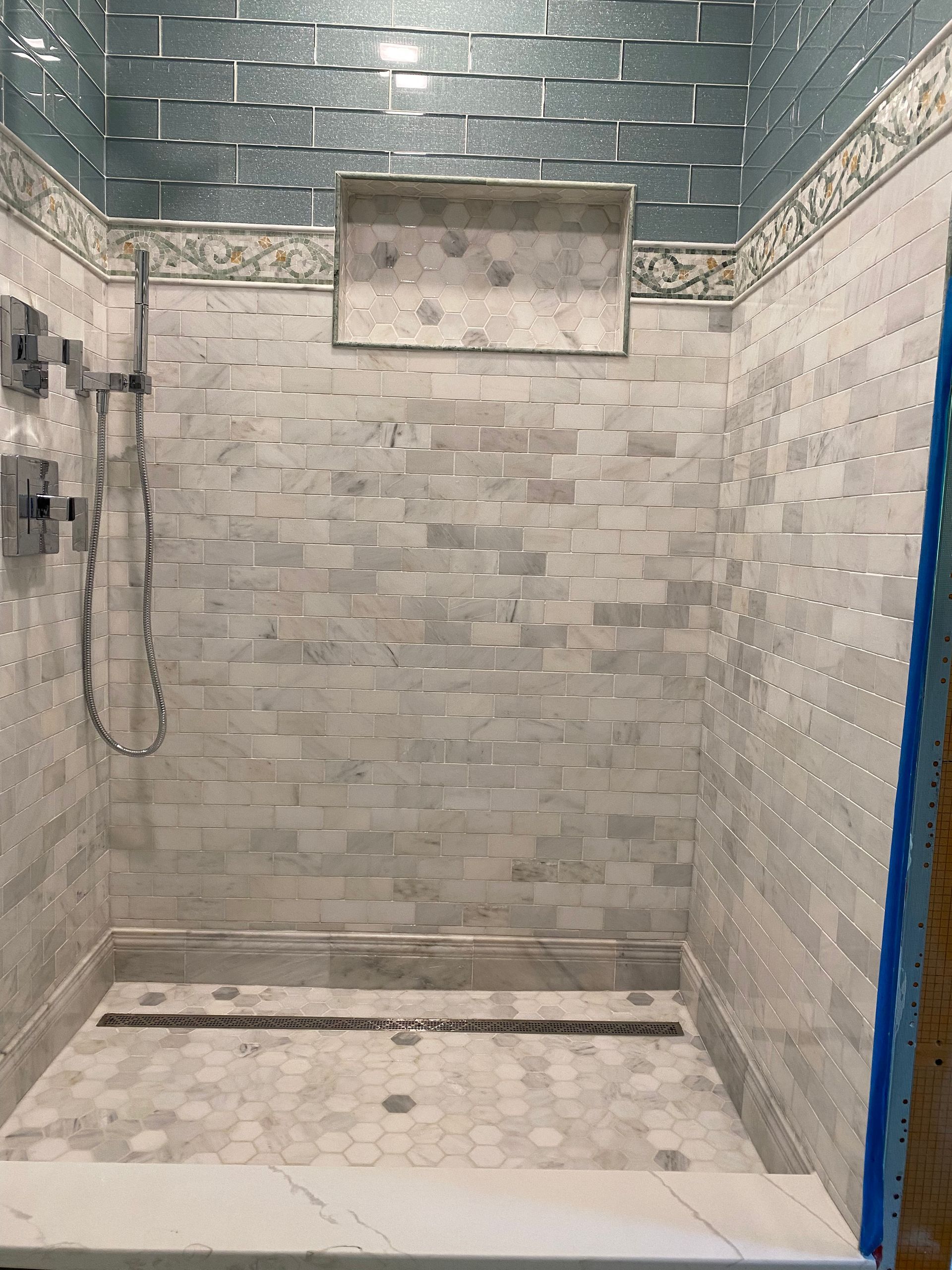 Tiled shower stall with wall-mounted showerhead and stone-gray walls