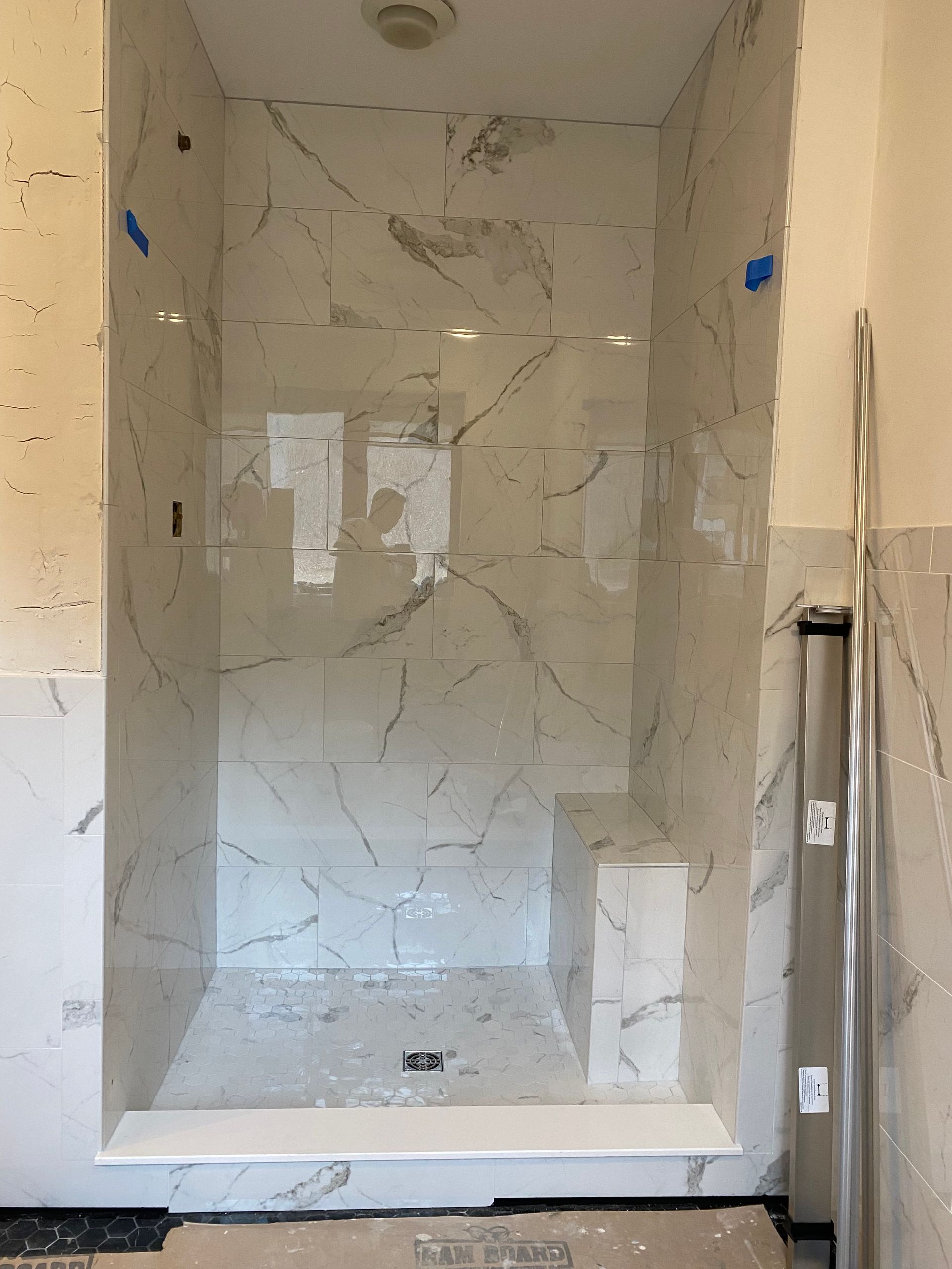 Empty tiled shower alcove with marble-look walls and a built-in shelf niche
