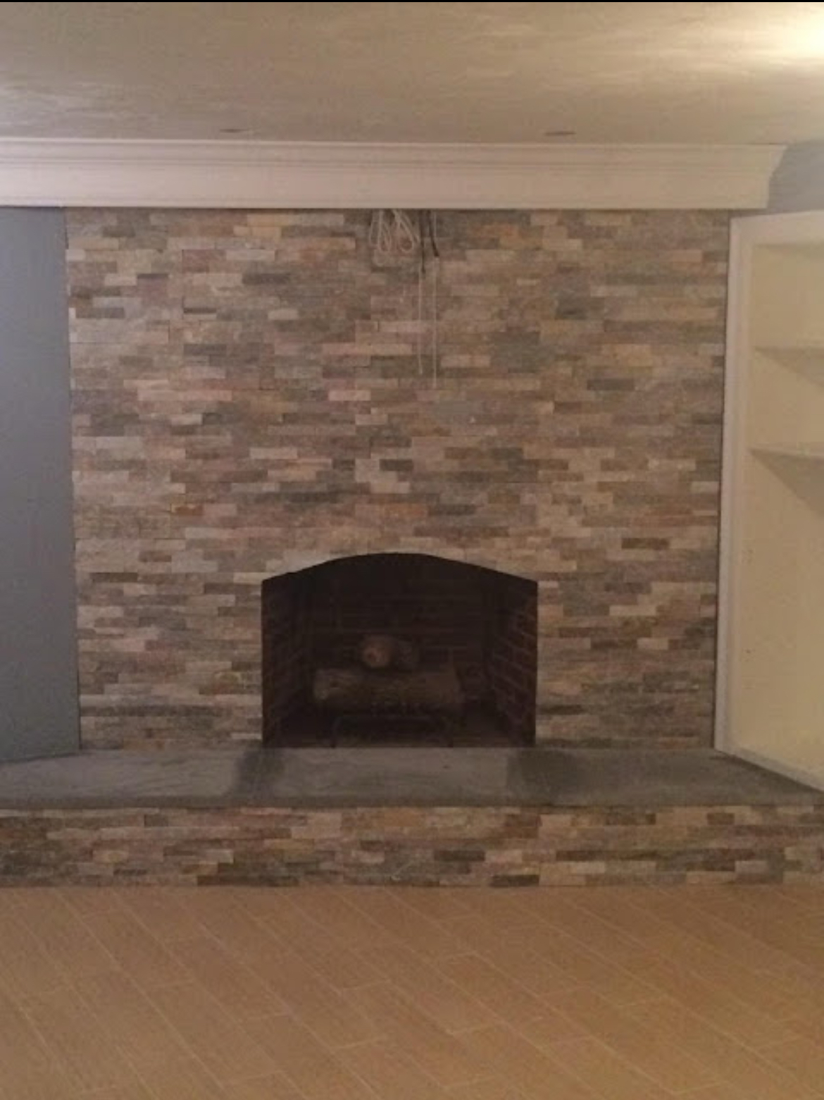 Brick fireplace with a raised hearth in an empty room, framed by white trim and built-in shelves.