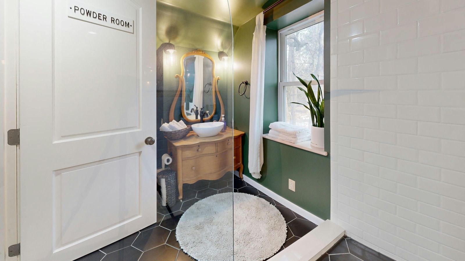 Tiled shower stall with a handheld showerhead, built-in shelf, and white bench seat.