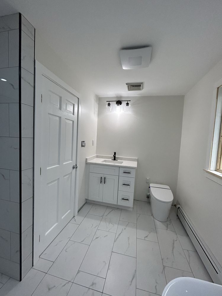 Stone-tiled shower alcove with two wall-mounted showerheads and a bench