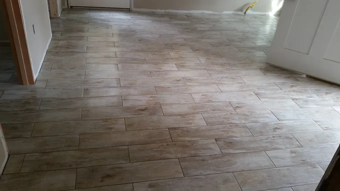 Empty room with light wood-look tile flooring and white walls, viewed from an open doorway