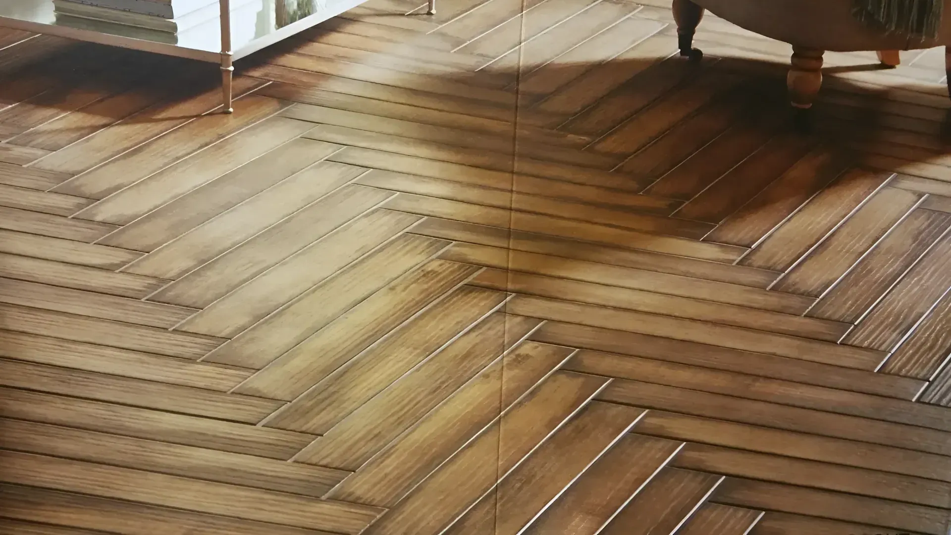 Herringbone wood floor in a sunlit room with furniture legs at the edges