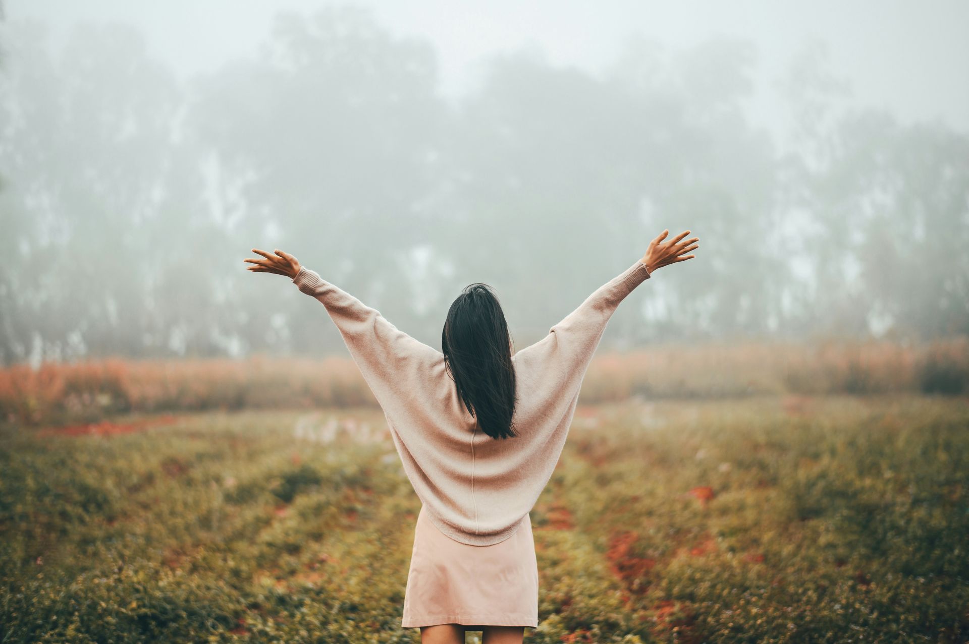 Person with arms raised standing in a misty field, symbolizing freedom and healing through mind-body integration.