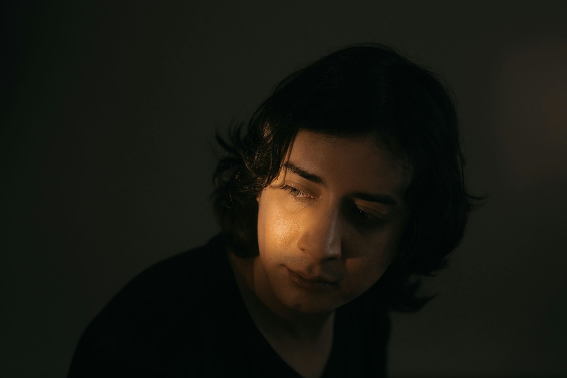 Person in shadow with a pensive expression, illustrating how trauma lives in the body beyond conscious awareness.