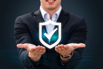 Hombre de traje que presenta un icono de escudo brillante con una marca de verificación, que simboliza seguridad.