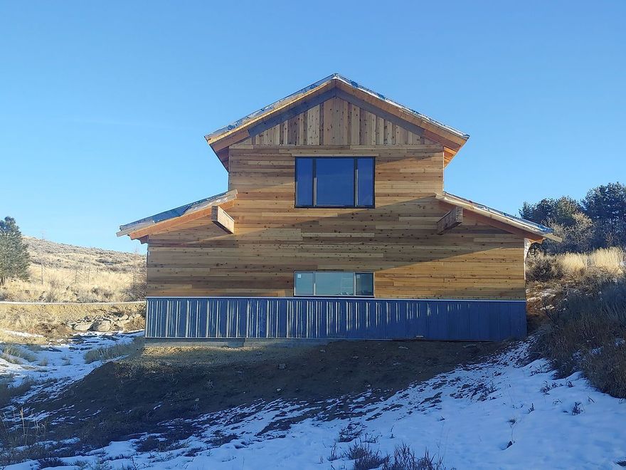 Snowy wooden cabin on a hillside under a clear blue sky