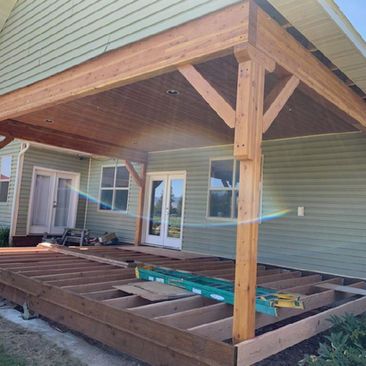 Partially built wooden covered patio deck attached to a house with exposed framing and support posts