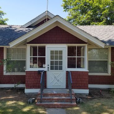 Front entrance of a red brick house with white trim, central white door, and small steps with railings
