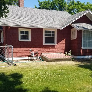 Red house exterior with two windows, lawn, and a small ramp by the side door