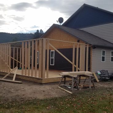 House under construction with exposed wooden framing on a porch addition