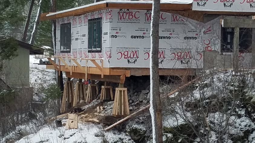 Partially built house on stilts in a snowy wooded area