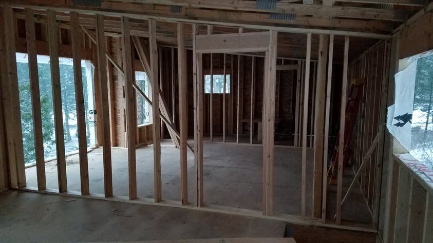 Interior of a house under construction with exposed wooden framing and unfinished walls.