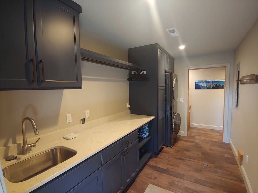 Long narrow kitchen with dark cabinets, light countertop, sink, refrigerator, and wood floor.