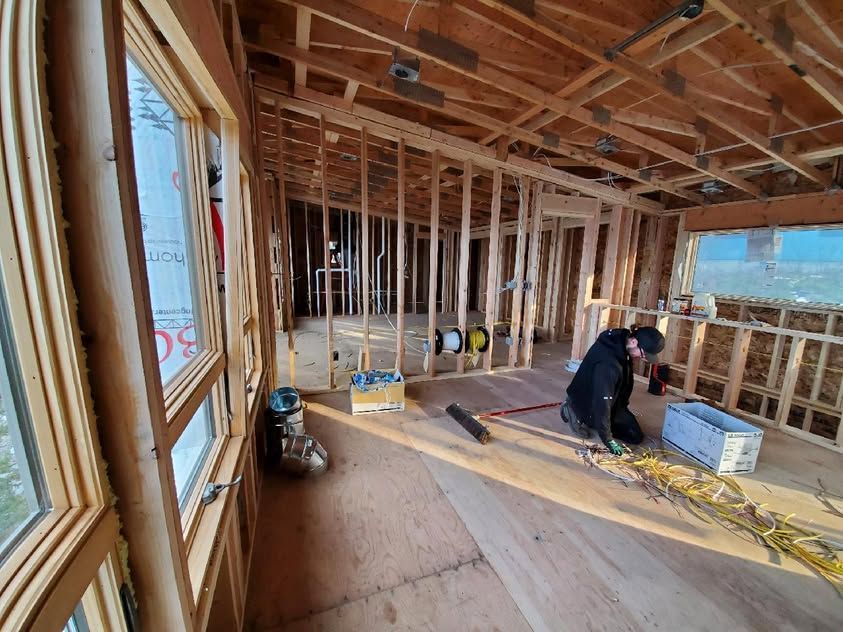 Partially framed room under construction with two workers, exposed wood beams, and tools on the floor