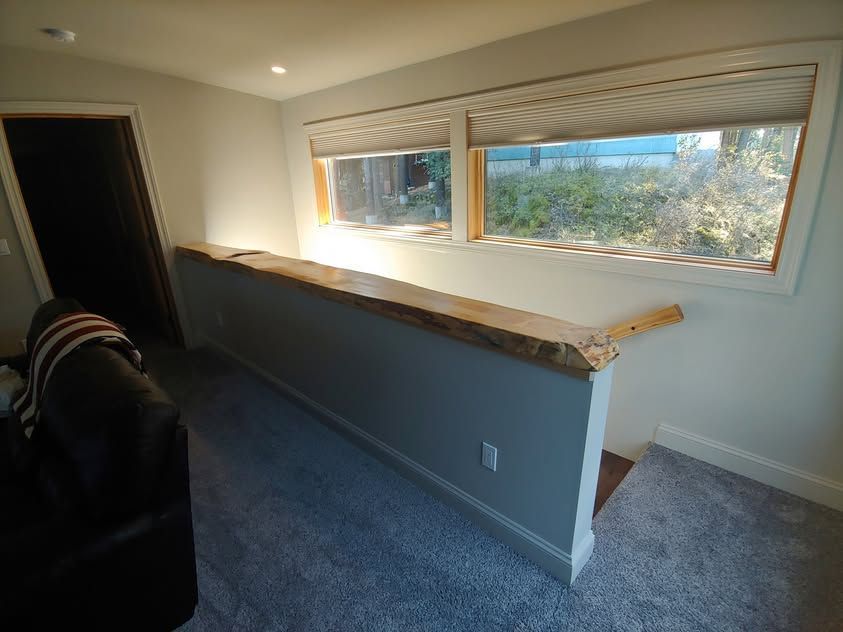 Living room with a half-demolished wall under windows and a carpeted floor
