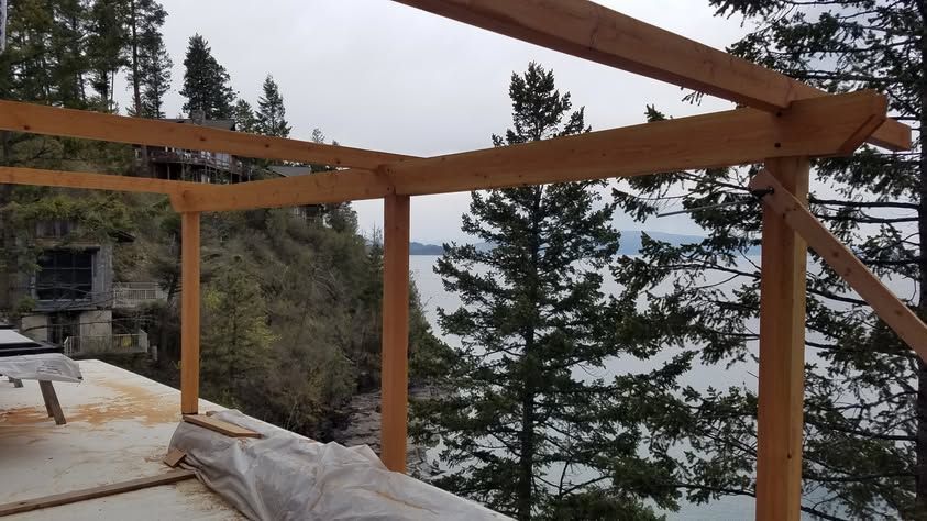 Partially built wooden deck frame with snow-covered ground and trees in the background