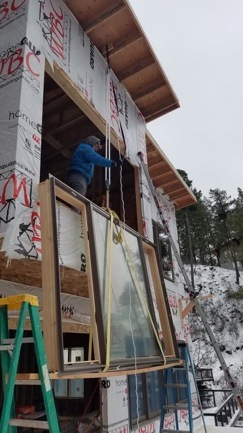 Worker on scaffolding installing windows on a snowy construction site