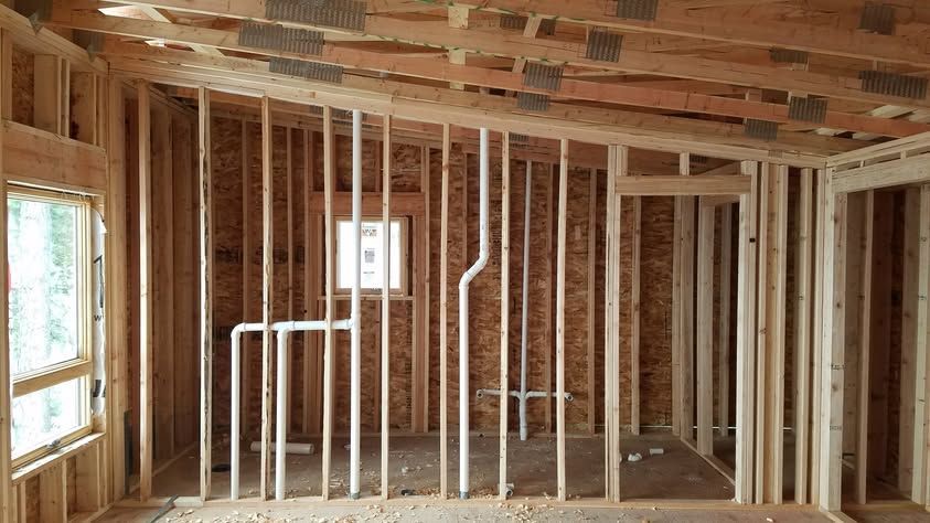 Partially framed interior of a house under construction with exposed wood studs and ceiling joists