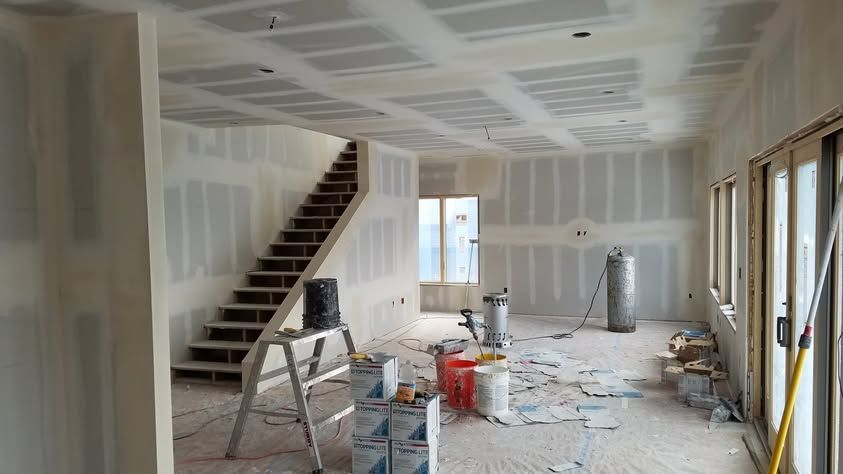 Unfinished room with drywall, staircase, tools, and construction debris on the floor.