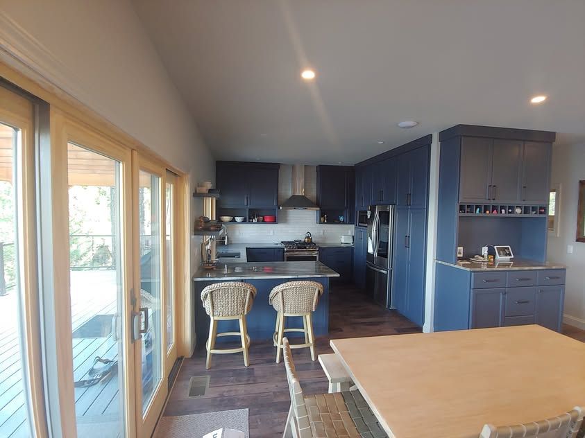 Modern kitchen with blue cabinets, island stools, and sliding glass doors to a patio