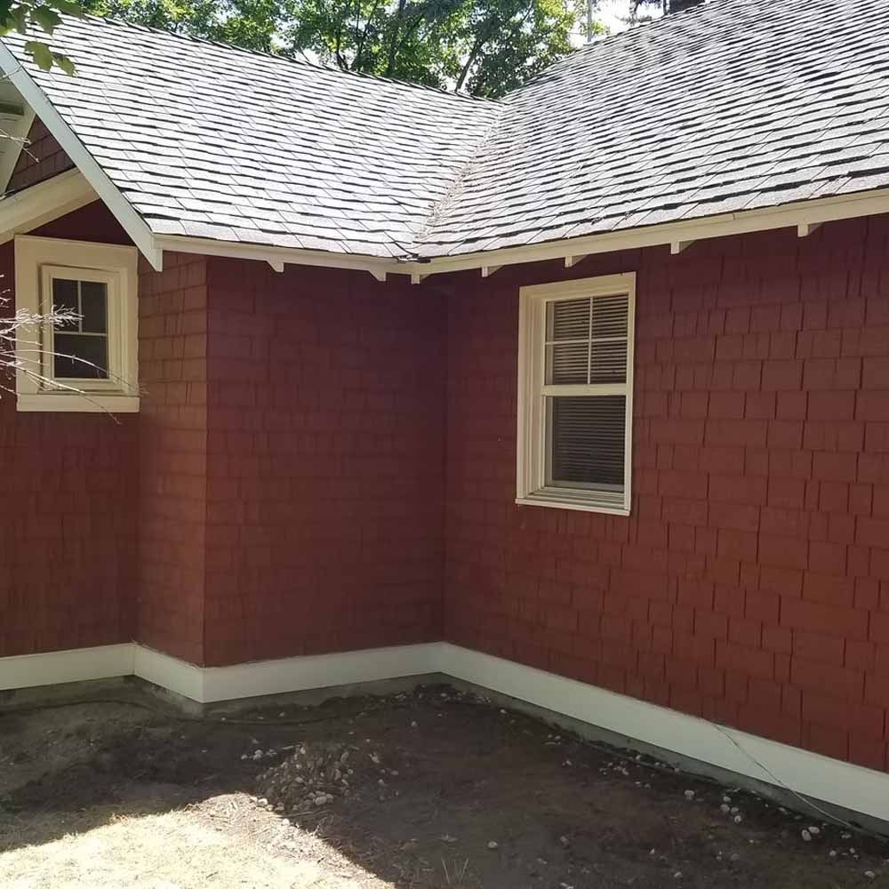 Red house exterior with white trim, two windows, and a shingled roof around a small courtyard