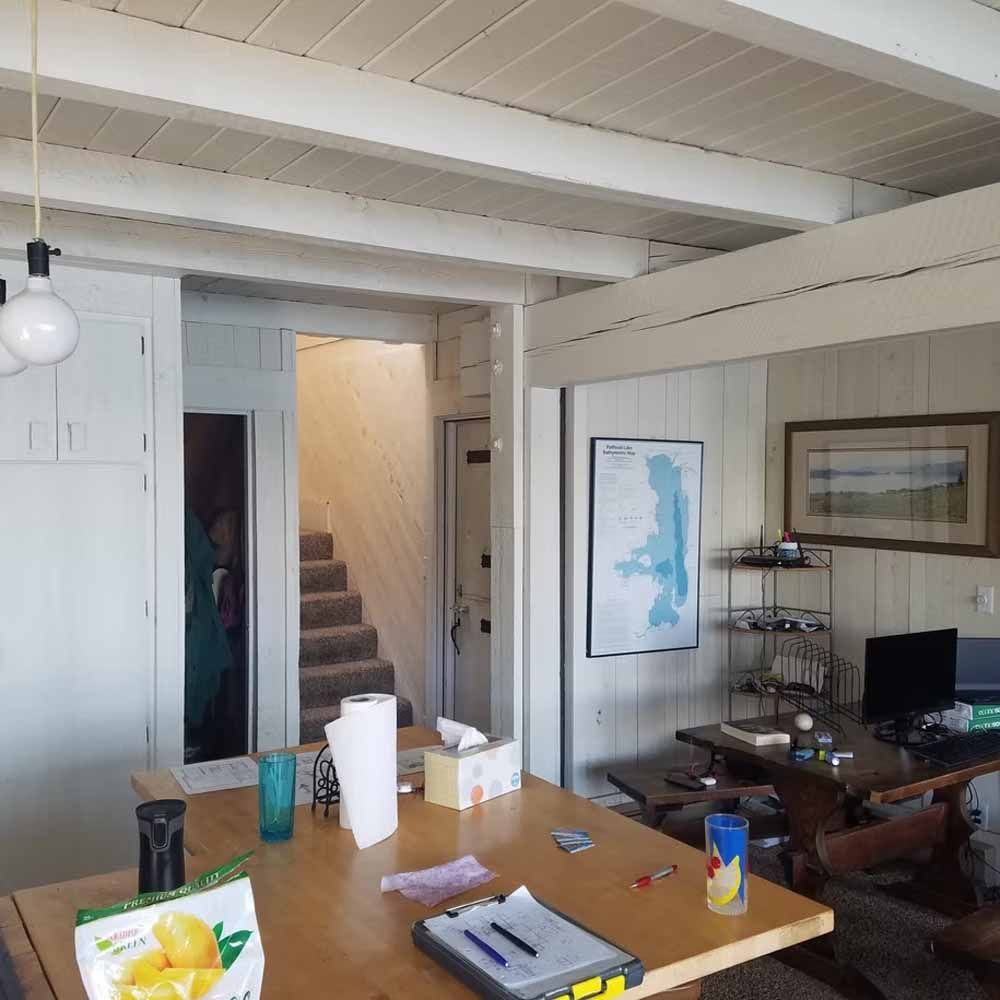 Open living room with dining table, staircase, desk, and map on the wall.