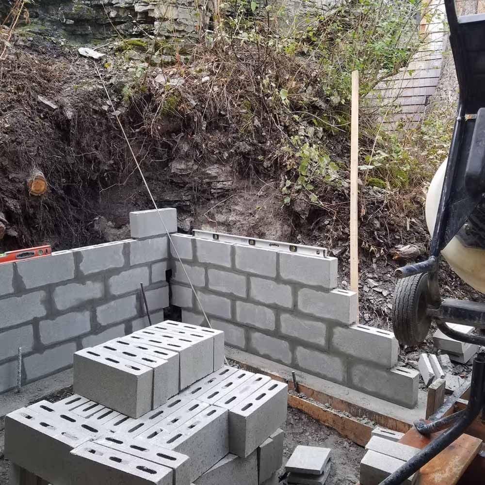 Partially built cinder block wall at a construction site with stacked blocks and a shovel nearby