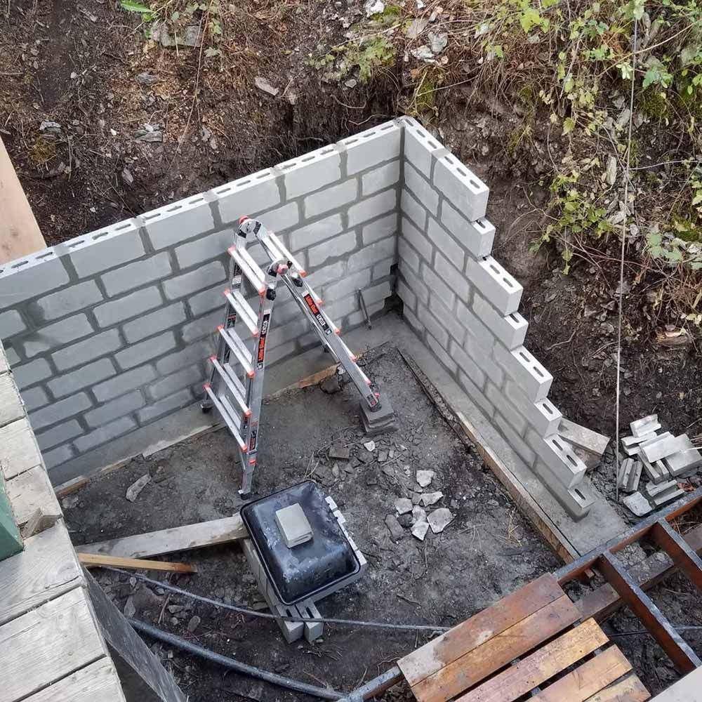 Partially built cinder block wall with a ladder in a small construction area