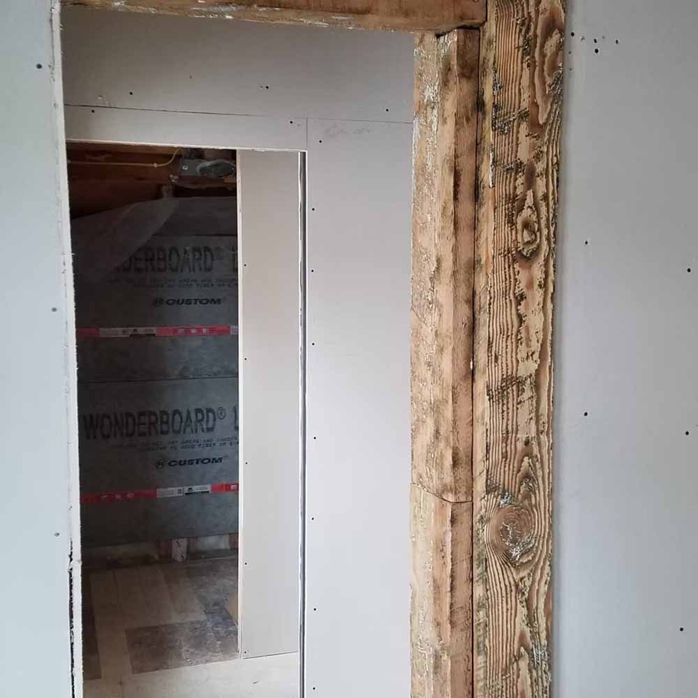 Partially finished doorway with exposed wood trim and drywall inside a construction area