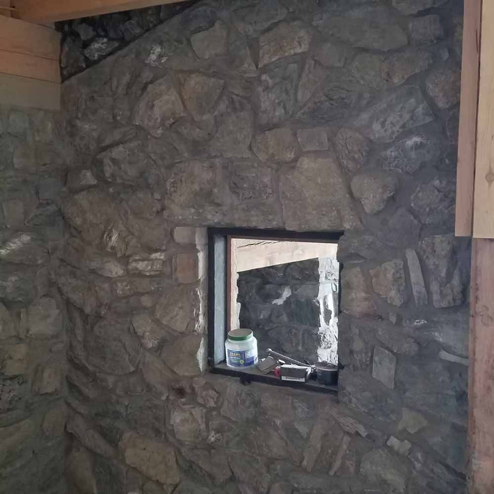 Stone fireplace wall with a small rectangular window and a paint can on the sill