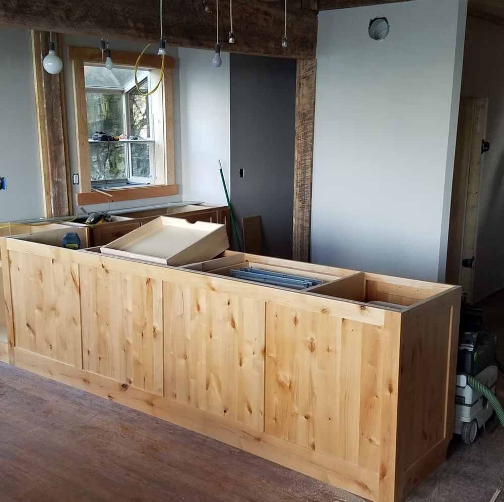 Wooden kitchen island under construction in a room with a window and unfinished walls