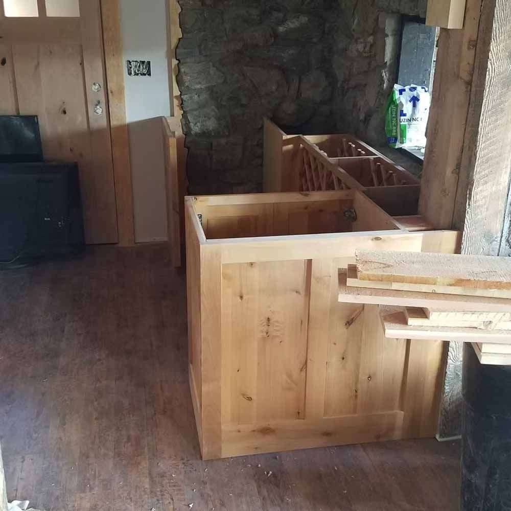 Wood-paneled room with a stone fireplace and a large unfinished wooden counter or cabinet in the foreground