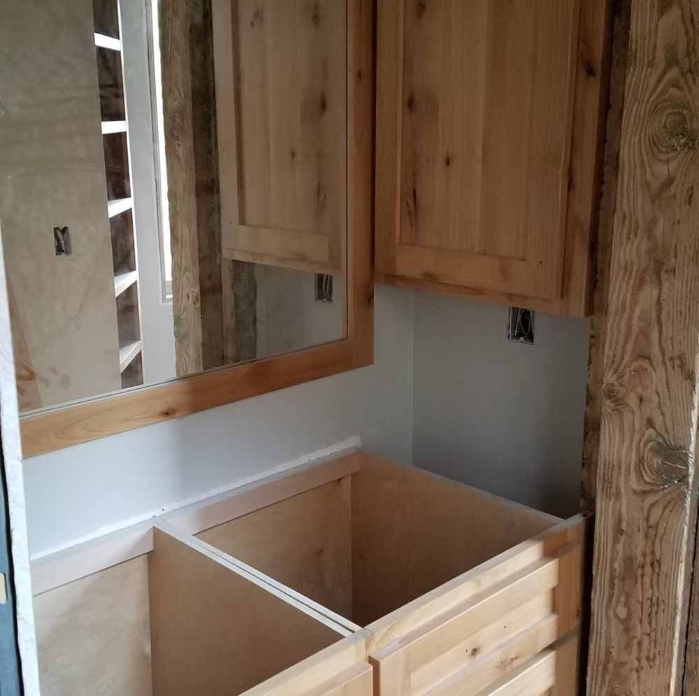 Partially built bathroom vanity with wood cabinets, countertop opening, and mirror trim