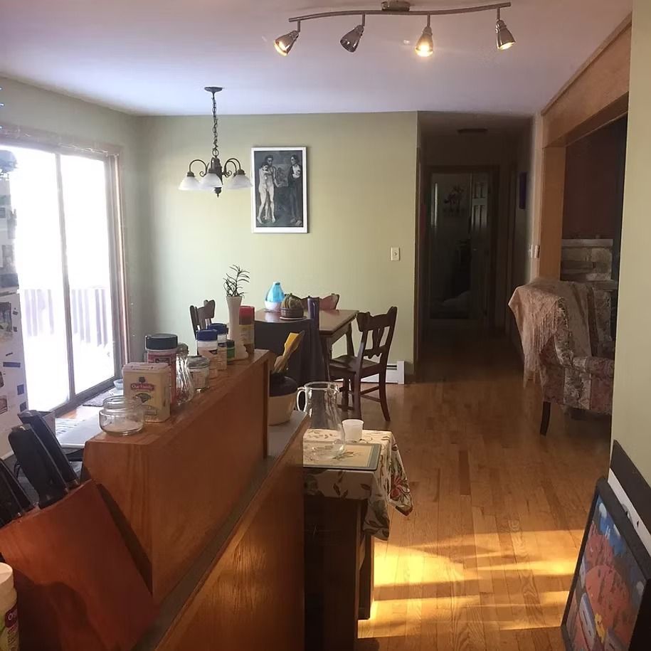 Sunlit dining room with wooden table, chairs, and a bright sliding glass door.