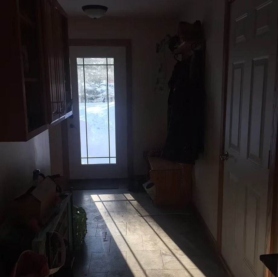 Dark hallway with sunlight streaming through a glass back door onto the floor.
