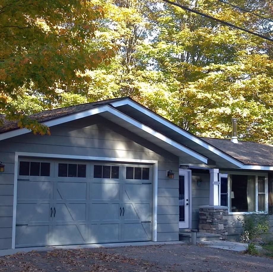 Gray garage attached to a house, framed by trees with autumn foliage