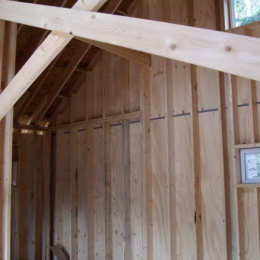 Inside a wooden barn, unfinished pine framing and walls with a small window on the right
