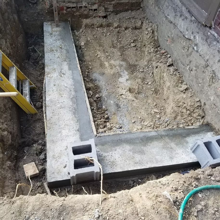 Concrete foundation trench with cinder blocks and rebar in an unfinished excavation area