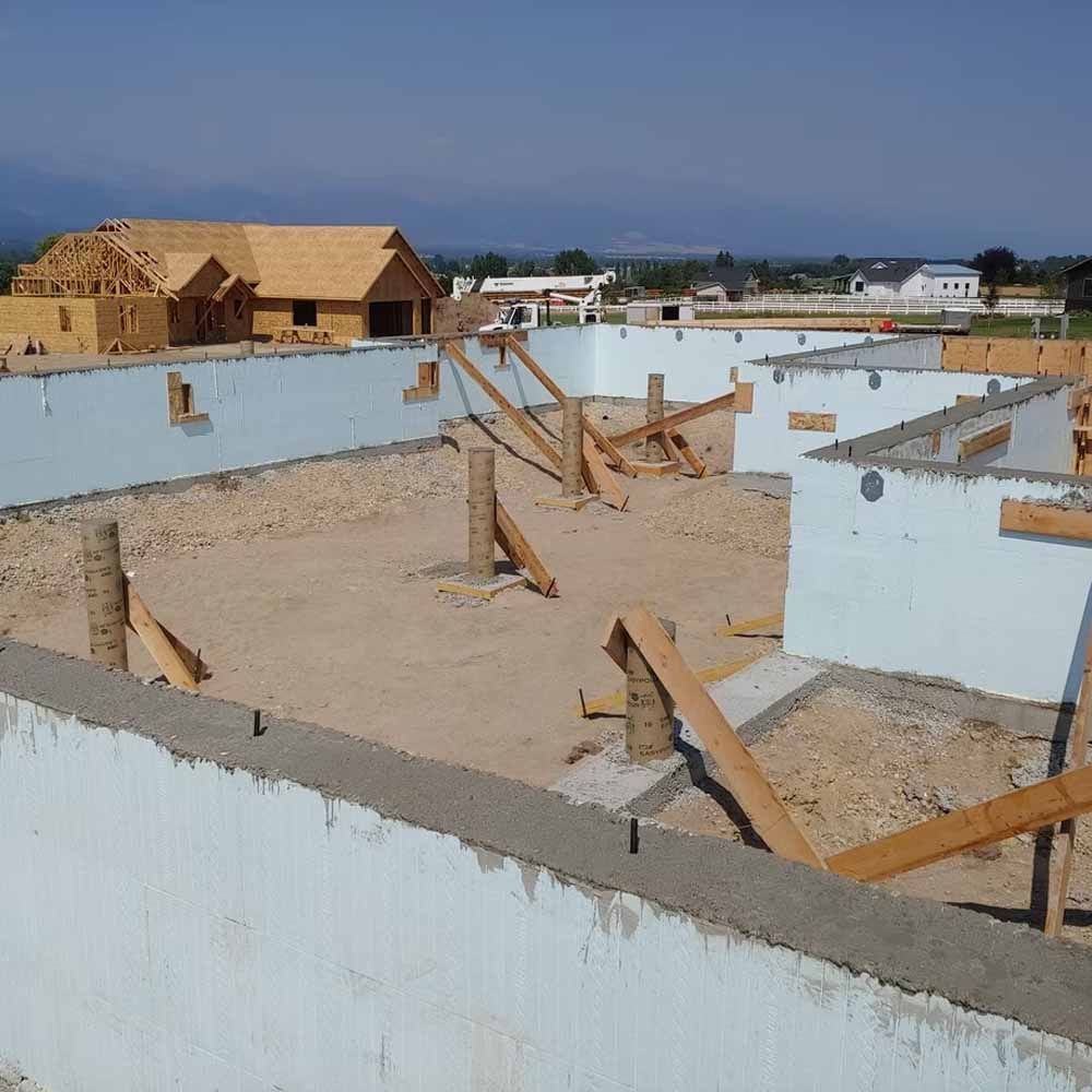 Partially built house foundations and white walls at a construction site under a clear sky