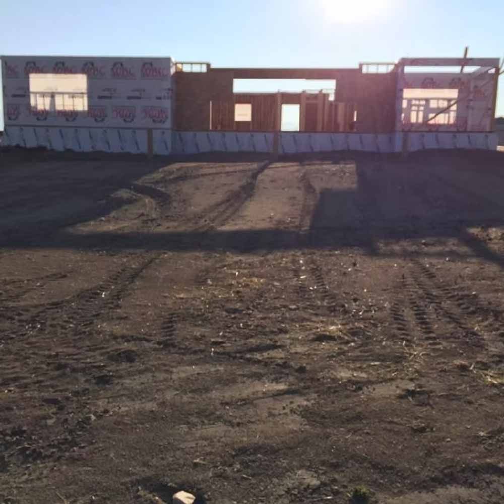 Partially constructed building on a dirt lot under bright sunlight