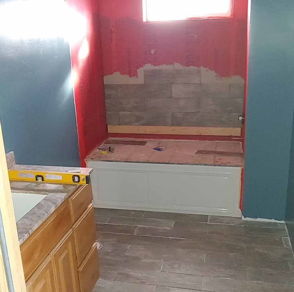 Partially renovated room with red and gray walls, a raised platform, and tiled floor