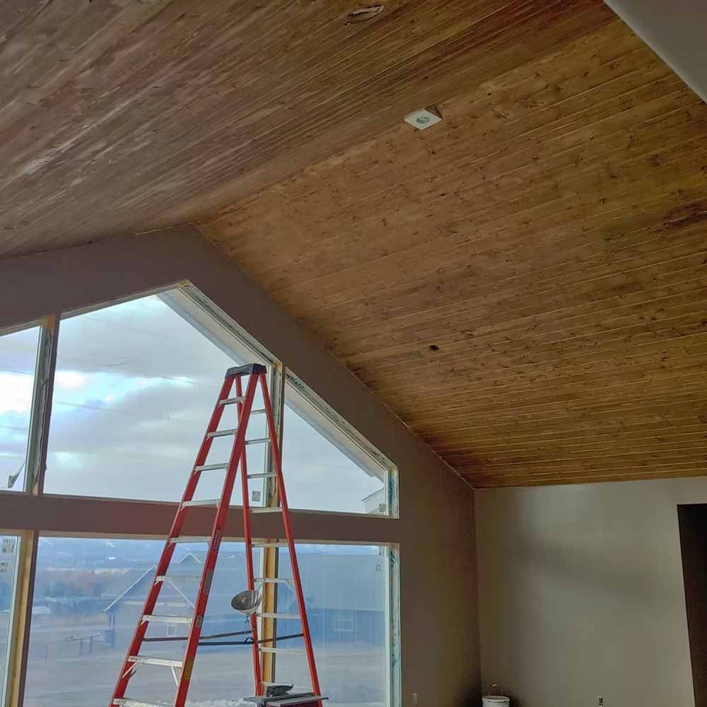 Red ladder in a room with a slanted wood ceiling and large windows overlooking a snowy landscape