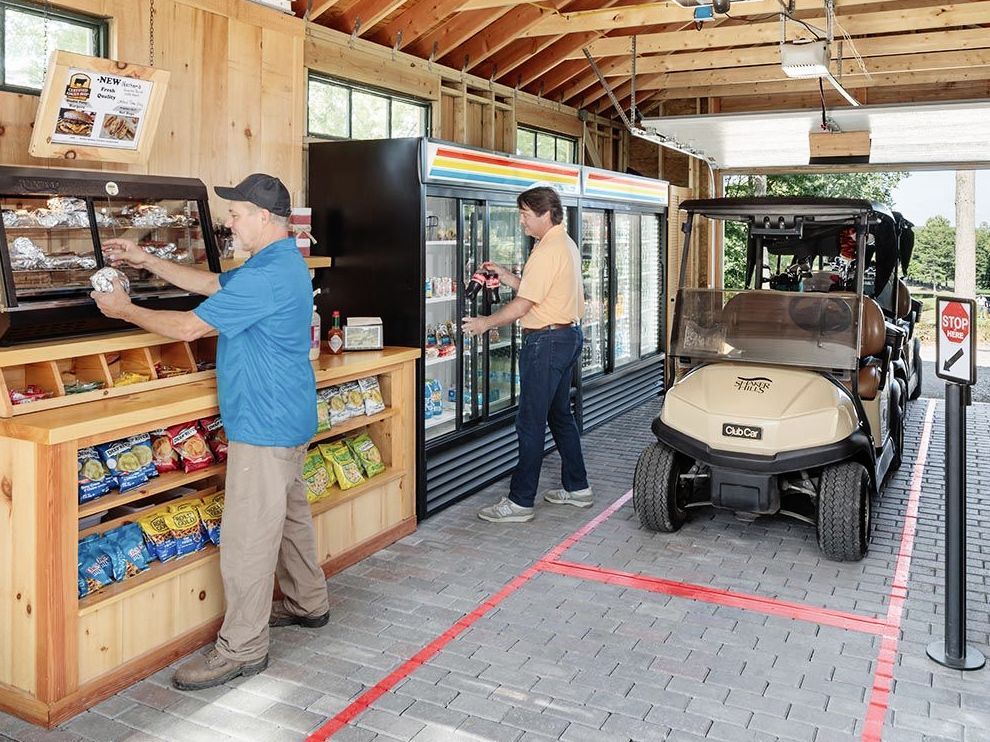Two men are standing in front of a golf cart in a store.
